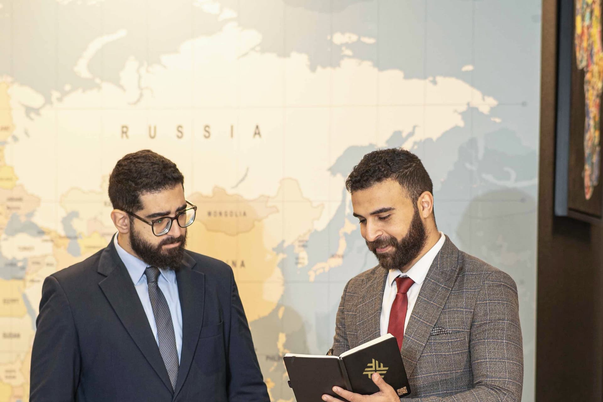 Two advisors reviewing a brief in front of the world map